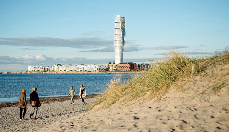 Människor promenerar vid stranden.