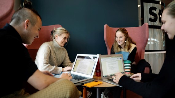 Fyra studenter pluggar tillsammans runt ett bord.