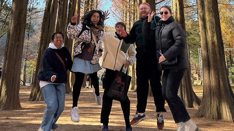 Fem glada studenter tar ett skutt i skogen.