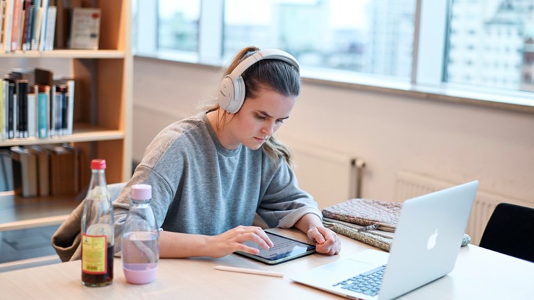Student med hörlurar i biblioteket.