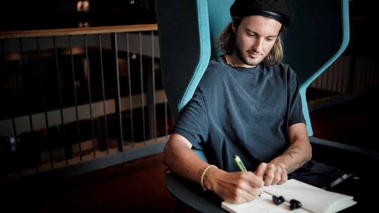 Student studerar i fotölj framför fönster.
