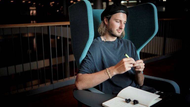 Student studerar i fotölj framför fönster.