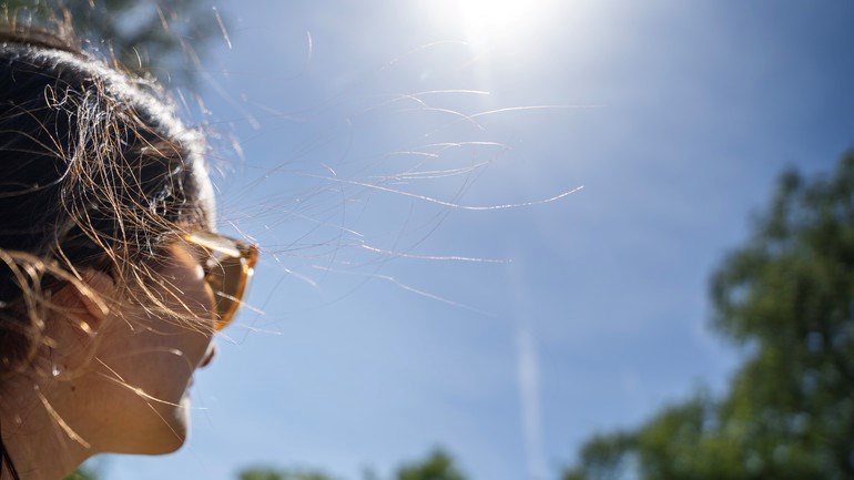 Person med solglasögon solar i park på sommaren.