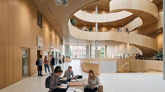 Atriet och den stora trappan sedd från kajsidan. Interiören går i ljust trä. AI-stödd visionsbild från C.F. Möller arkitekter.