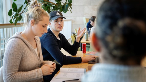 Studenter vid bord i biblioteket