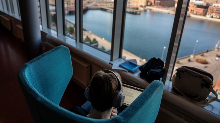 Student sitter i fåtölj framför fönster.