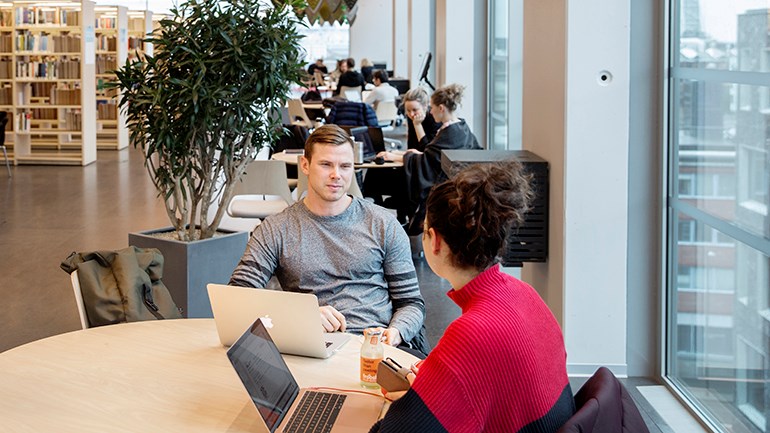 Studenter pratar på biblioteket