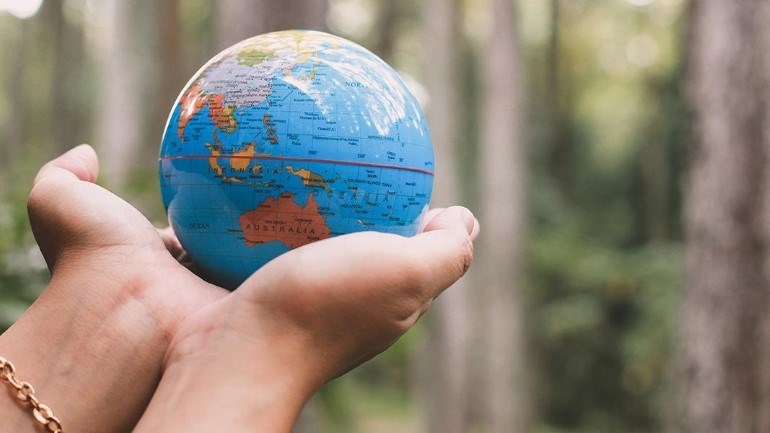 Holding an Earth-shaped ball.