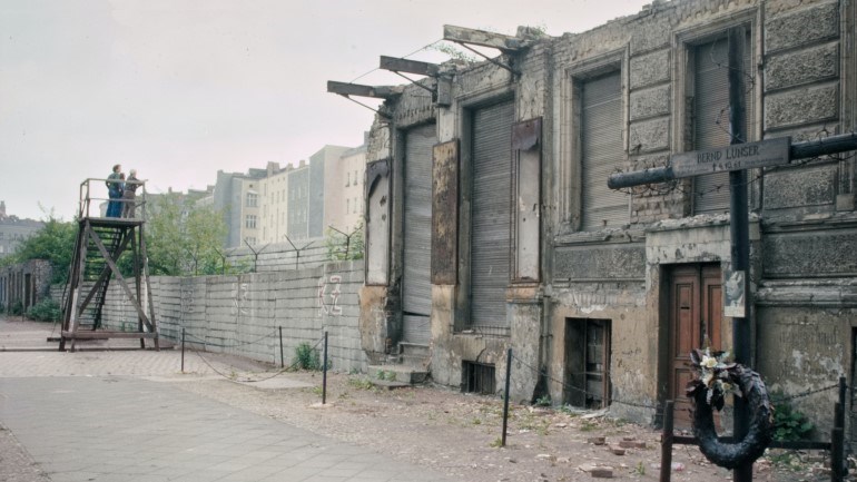 Soldater vid en mur och ett raserat hus.