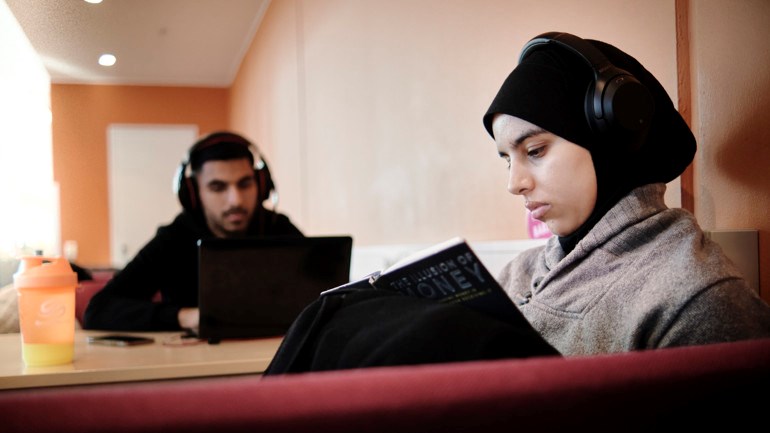 Student med hörlurar läser i bok