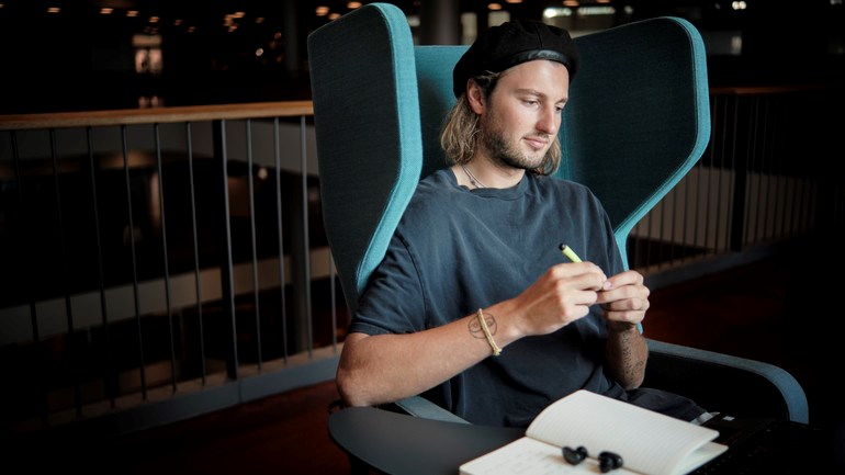 Student studerar i fotölj framför fönster.