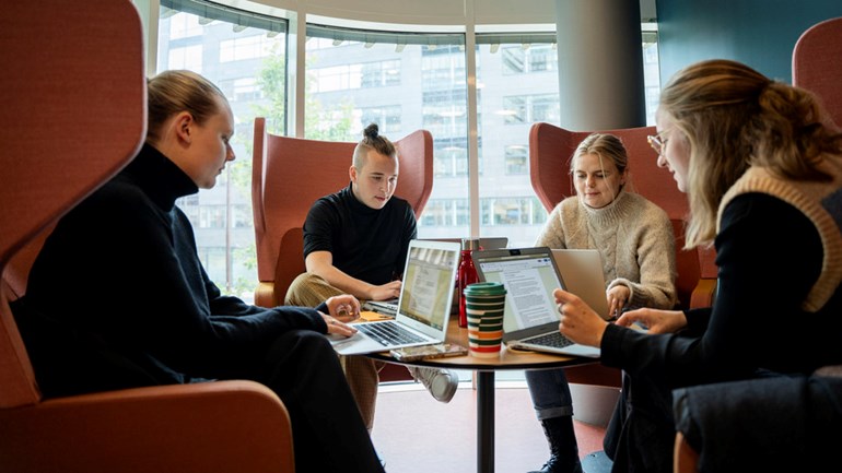 Fyra studenter pluggar tillsammans runt ett bord.